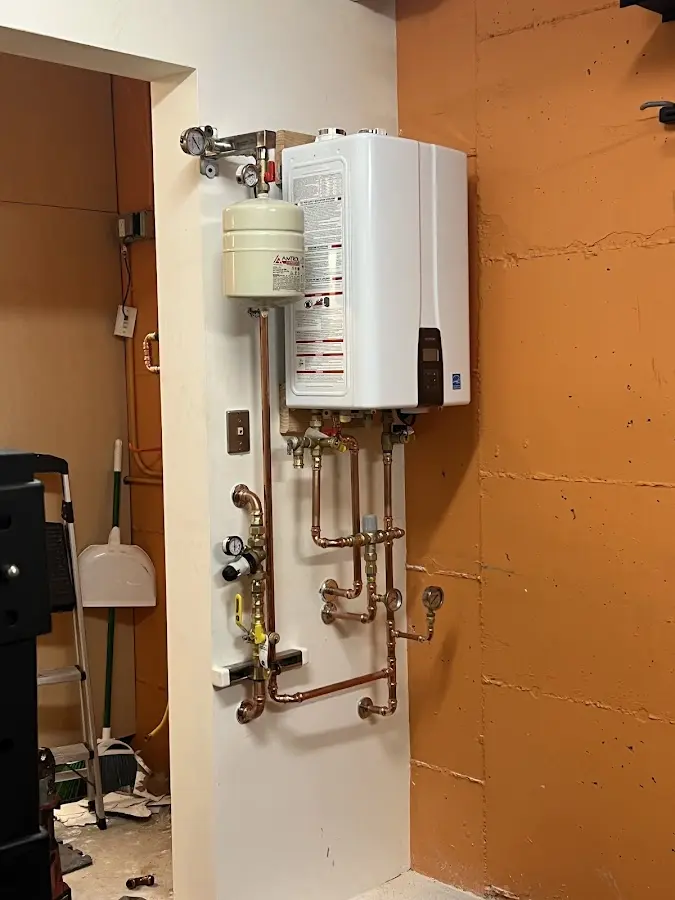 Plumbing technician inspecting water heater connections in Burrell